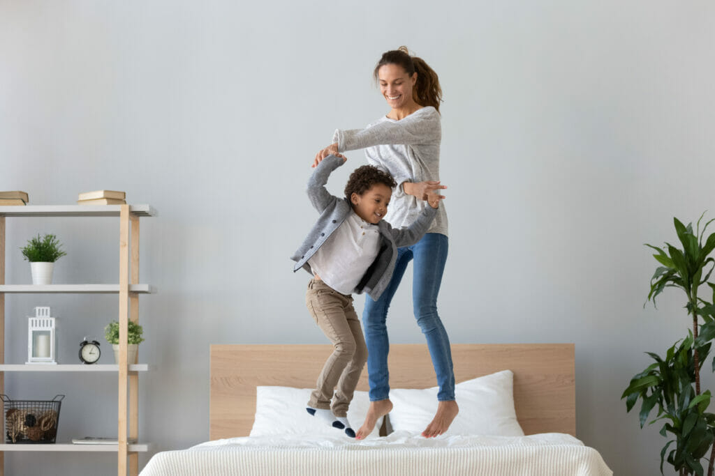 moeder en kind die op het bed springen
